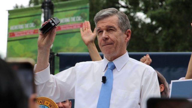 FILE - North Carolina Democratic Gov. Roy Cooper affixes his veto stamp to a bill banning nearly all abortions after 12 weeks of pregnancy at a public rally, May 13, 2023, in Raleigh, N.C. Transgender rights take center stage in North Carolina again Wednesday, Aug. 16, as GOP supermajorities in the General Assembly attempt to override the governor's vetoes of legislation banning gender-affirming health care for minors and limiting transgender participation in school sports. (AP Photo/Hannah Schoenbaum, File)